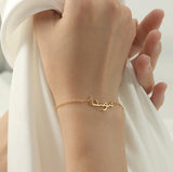 A arabic 18k gold bracelet with a custom nameplate on a person's wrist.