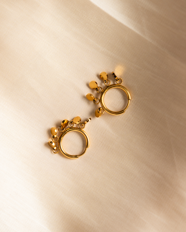 Gold earrings on a beige background