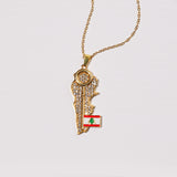 Gold necklace with a pendant shaped like a map of Lebanon featuring the Lebanese flag on a light gray background.